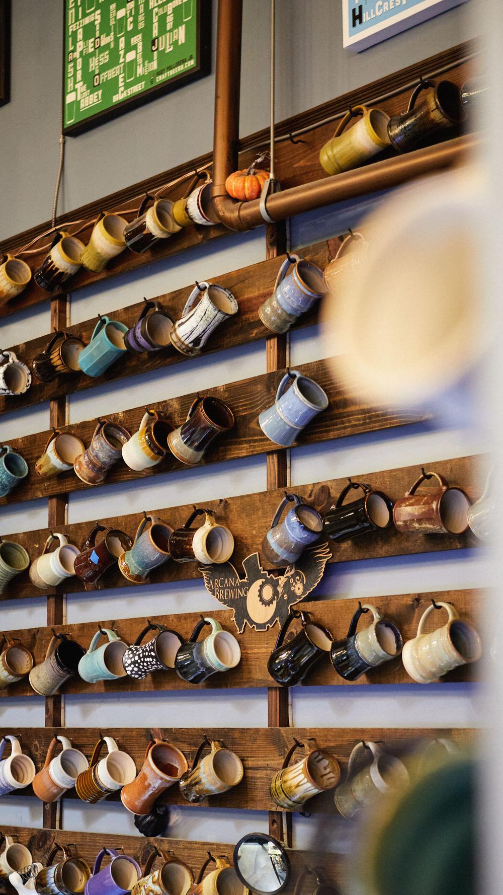 Wall of mug club mugs hanging on wooden rails in the Arcana taproom